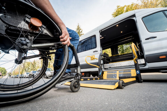 Photo d'une personne en fauteuil roulant face à petit bus adapté avec une plateforme élévatrice. - Agrandir l'image, fenêtre modale