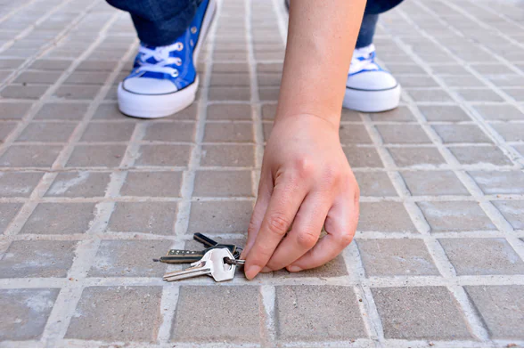Photo d'une personne qui ramasse des clés par terre. - Agrandir l'image, fenêtre modale