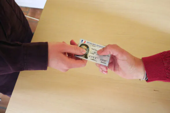 Photo d'une personne qui donne sa carte d'identité à une autre. - Agrandir l'image, fenêtre modale