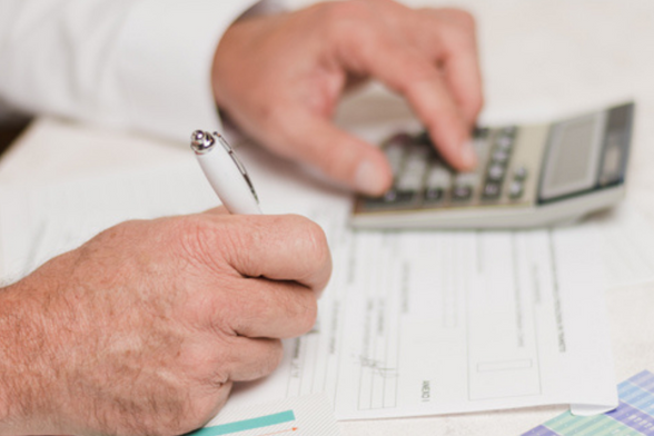 Photo d'un homme qui écrit en se servant d'une calculatrice. - Agrandir l'image, fenêtre modale