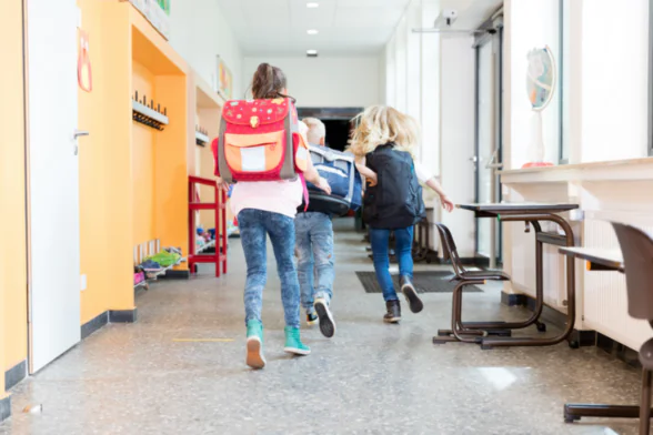 Photo de 3 enfants qui courent, avec leur sac sur le dos, dans le couloir d'une école. - Agrandir l'image, fenêtre modale