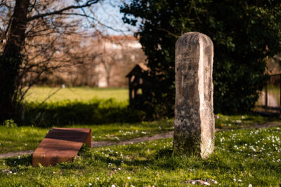 Petite stèle en pierre d'environ 50 cm posée dans un espace enherbé - Agrandir l'image 1 sur 1, fenêtre modale
