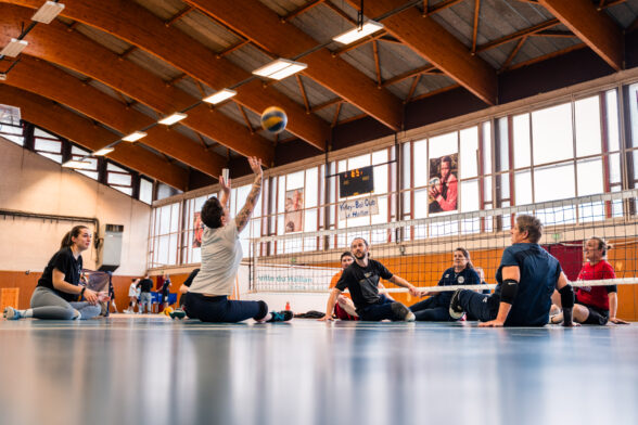 Personnes assises au sol jouant au volley assis dans un gymnase - Agrandir l'image, fenêtre modale